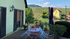 Une terrasse avec une table ronde et des chaises, un petit banc rouge et des plantes en pot.