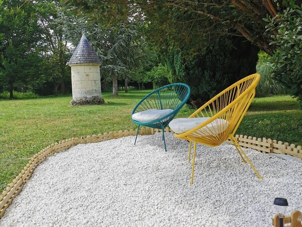 A garden with two chairs, a stone pillar, and a hedge. - Charming Cottage Near Le Mans: Private Estate, Zoo, Castles, Vineyards, Sleeps 4 (Mayet)