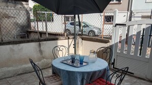Un pati amb una taula rodona, dues cadires i una ombrel·la de taula.