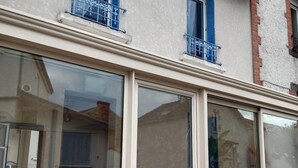 Fachada d'un edifici amb grans finestres de vidre, una porta i un petit balcó amb barana metàl·lica.