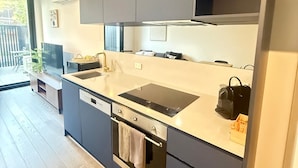 A modern kitchen with dark cabinets, a black countertop, and a built-in oven. - CBD | Pool | Sleeps 4 | Parking | Pets (Reid)