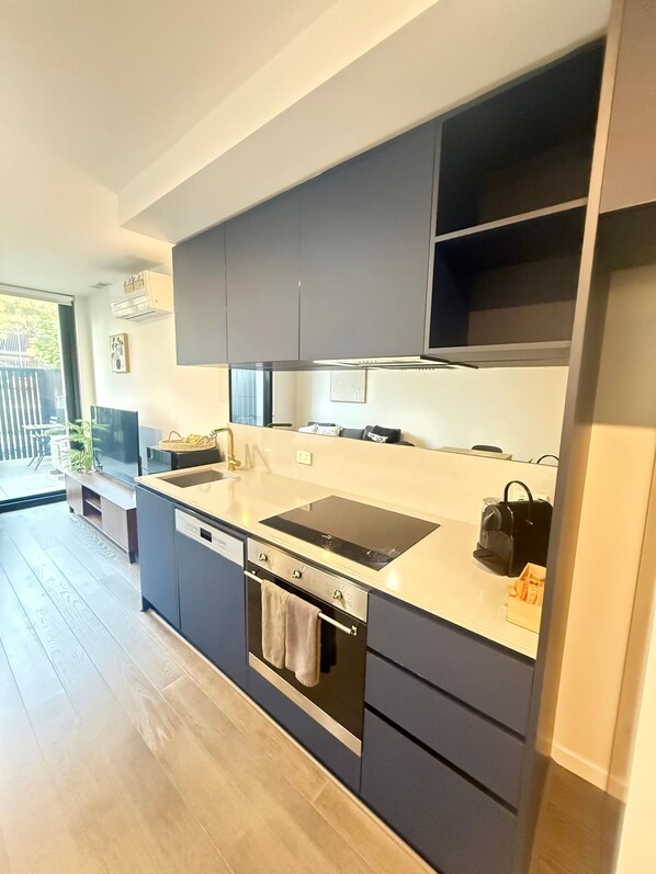 A modern kitchen with dark cabinets, a black countertop, and a built-in oven. - CBD | Pool | Sleeps 4 | Parking | Pets (Reid)