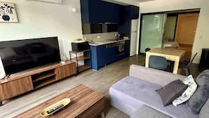 A modern living room with a flat-screen TV, wooden coffee table, and a grey sofa. - CBD | Pool | Sleeps 4 | Parking | Pets (Reid)