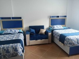 Un dormitorio con dos camas, una mesita de noche y un sofá azul.