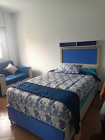 Un dormitorio con una cama, cabecera azul y colcha estampada.