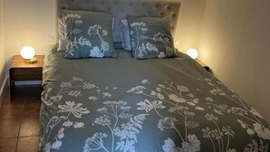 A neatly made bed with floral bedding, two bedside lamps, and a wooden nightstand.