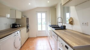 A modern kitchen with a built-in oven, a stove, and a washing machine.