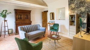 A living room with a sofa, two armchairs, a coffee table, a wooden cabinet, a mirror, and a painting on the wall.