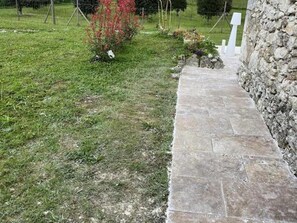 Stroll along the winding stone pathway to a serene outdoor space surrounded by lush greenery.