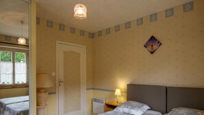 A bedroom with two beds, a door, a window, and a wall-mounted lamp. - Charming house in Prats-du-Périgord with enclosed garden (Prats-du-Périgord)