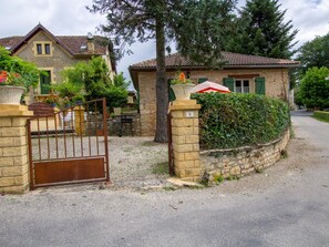 A residential property with a gated entrance, stone walls, and a paved driveway.