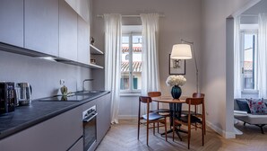 A modern kitchen with a dining area, featuring a built-in oven, a coffee maker, and a table with chairs.
