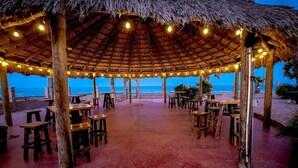 An outdoor dining area with thatched roofs and string lights, overlooking the beach. - Rancho Percebu Beach Studio 6 (San Felipe)