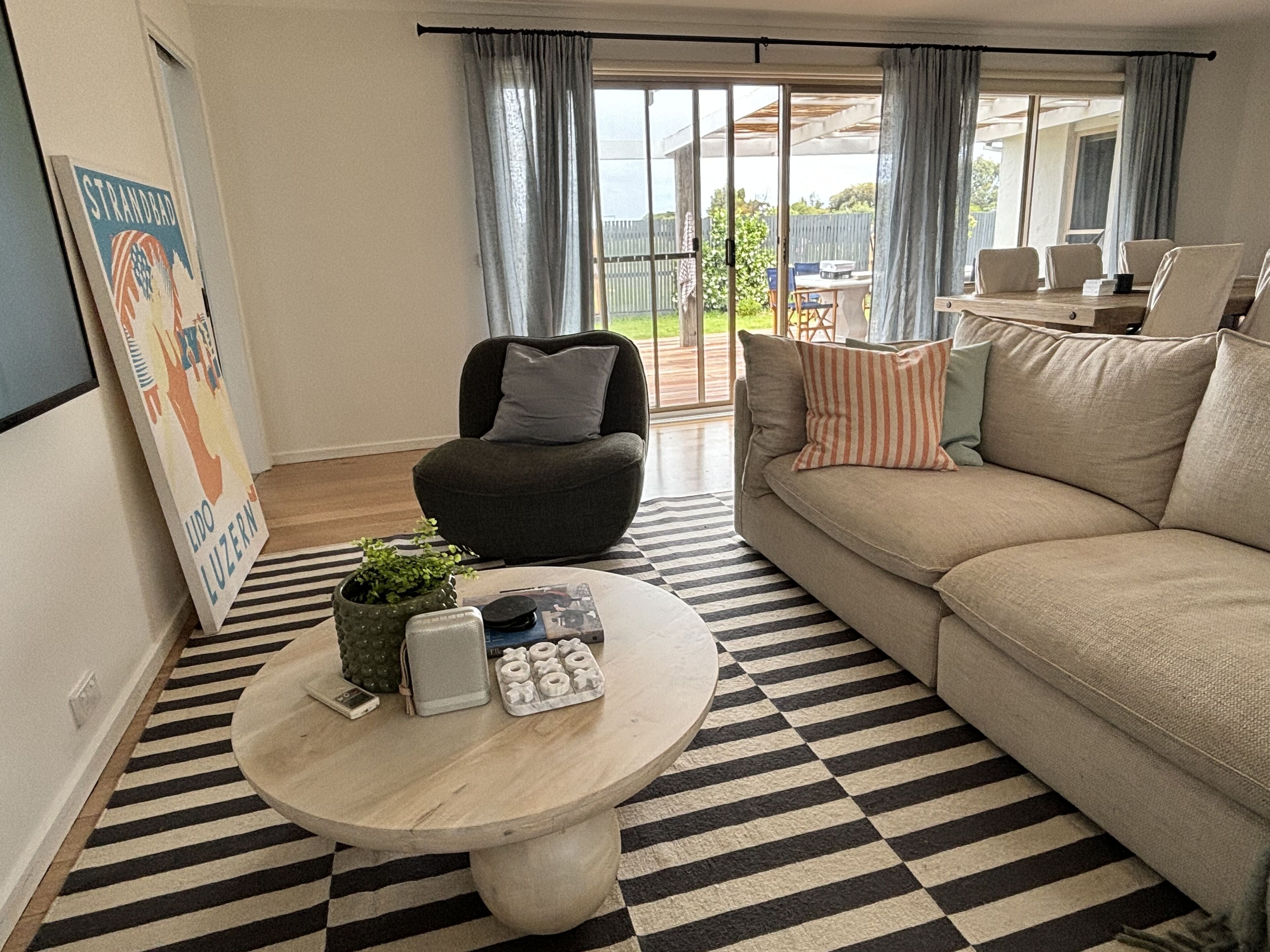 Un salon avec un canapé, une table basse ronde, un fauteuil et une vue sur l’extérieur.