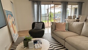 Un salón con un sofá, una mesita redonda, una silla y vistas al exterior.