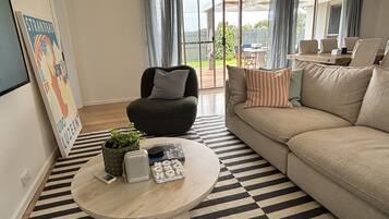 Un salon avec un canapé, une table basse ronde, un fauteuil et une vue sur l’extérieur.