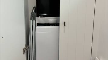 A compact laundry room with a washing machine and dryer, a small window, and a door with a metal handle.