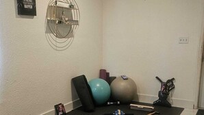 A home gym with exercise equipment, a yoga mat, and a motivational quote on the wall.