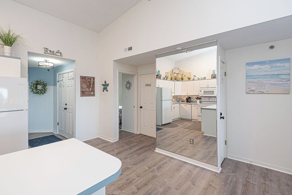 A modern kitchen with white cabinets, a microwave, and a dining area with a white table.