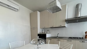 Cozinha moderna com armários brancos, fogão a gás e uma mesa de jantar com cadeiras.