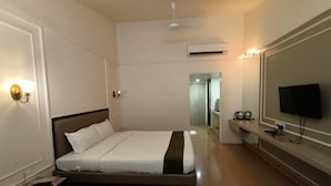 Habitación de hotel con cama, televisión montada en la pared, mesita de noche, escritorio y aire acondicionado.