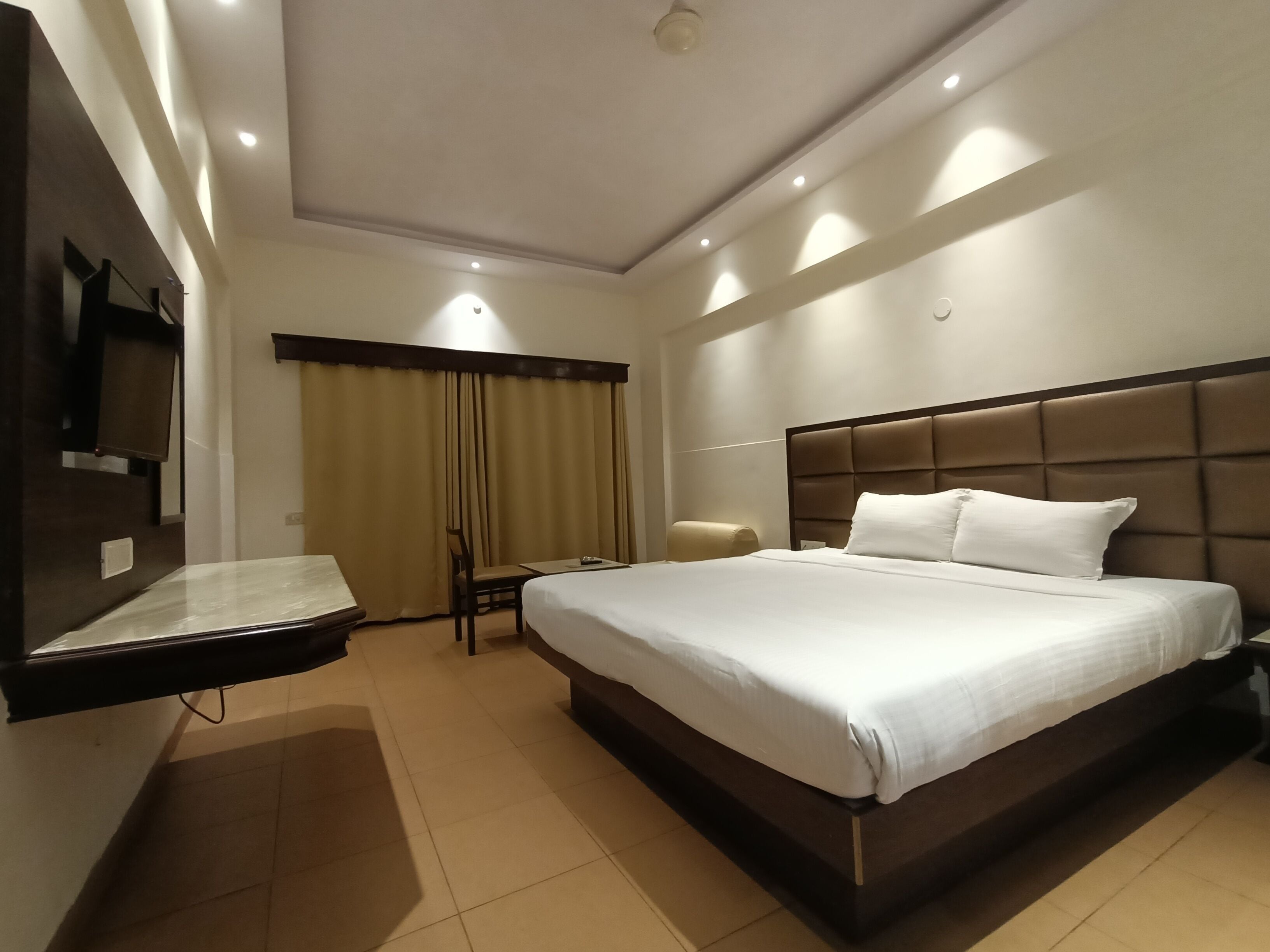 Habitación de hotel con una cama grande, un televisor de pantalla plana en la pared, un escritorio y una silla.