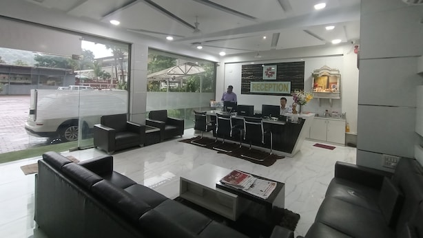 Un área de recepción con mostrador, sofás de cuero negro, una mesa de centro y un ventanal con vistas al exterior.