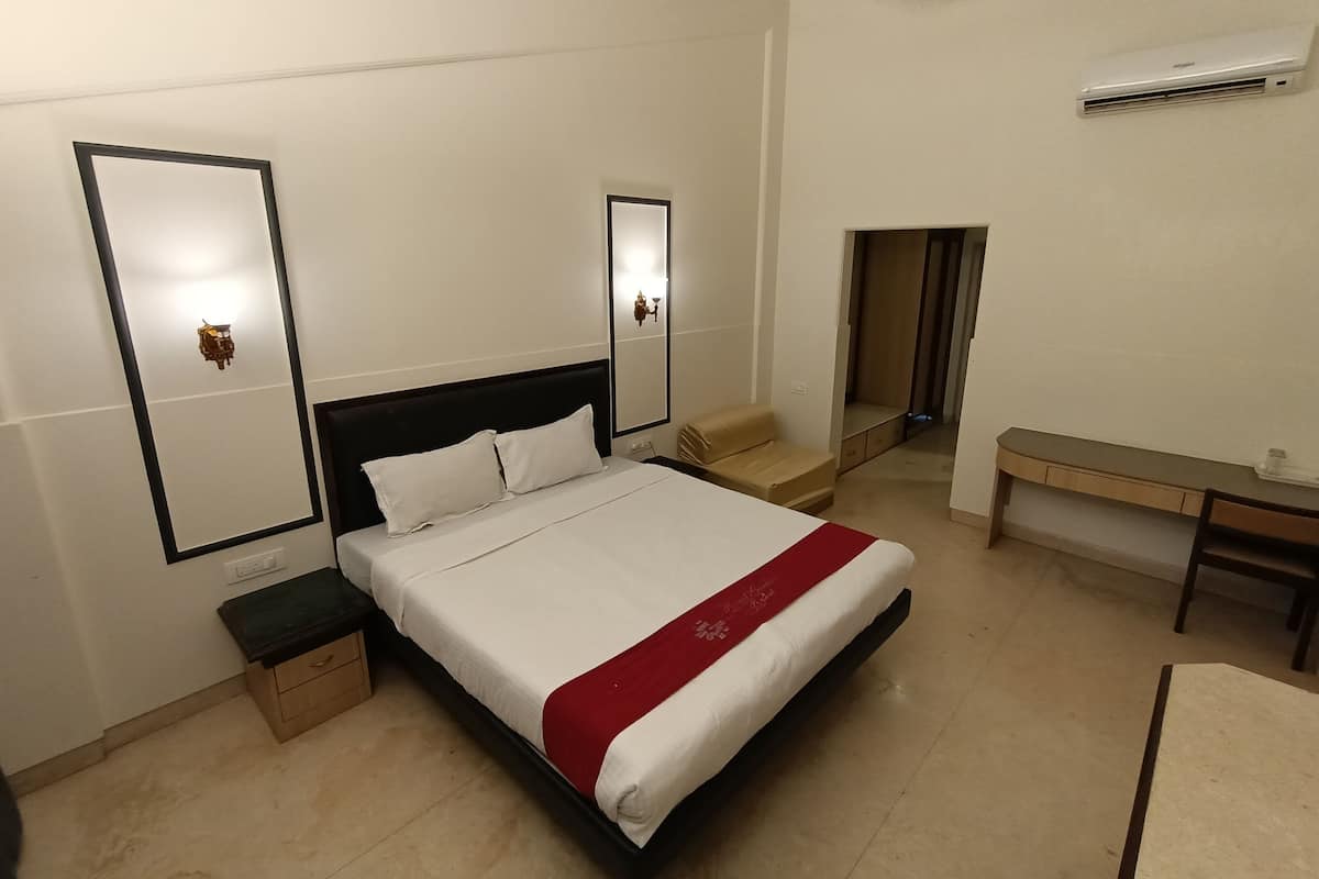 Quarto de hotel com uma cama, mesas de cabeceira, uma escrivaninha e um espelho.