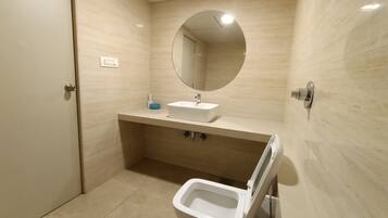 A modern bathroom with a white sink, a round mirror, and a toilet.