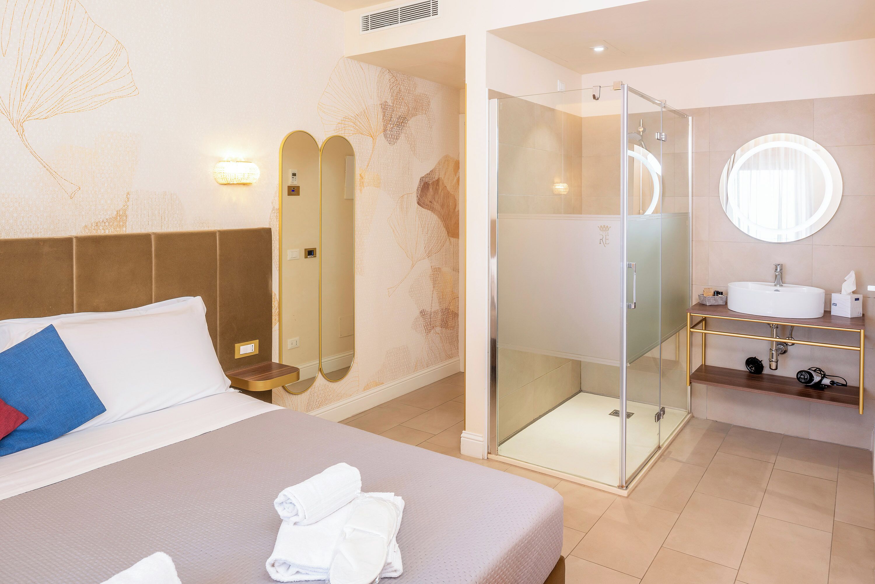A hotel room with a bed, a shower, and a bathroom with a sink and mirror.