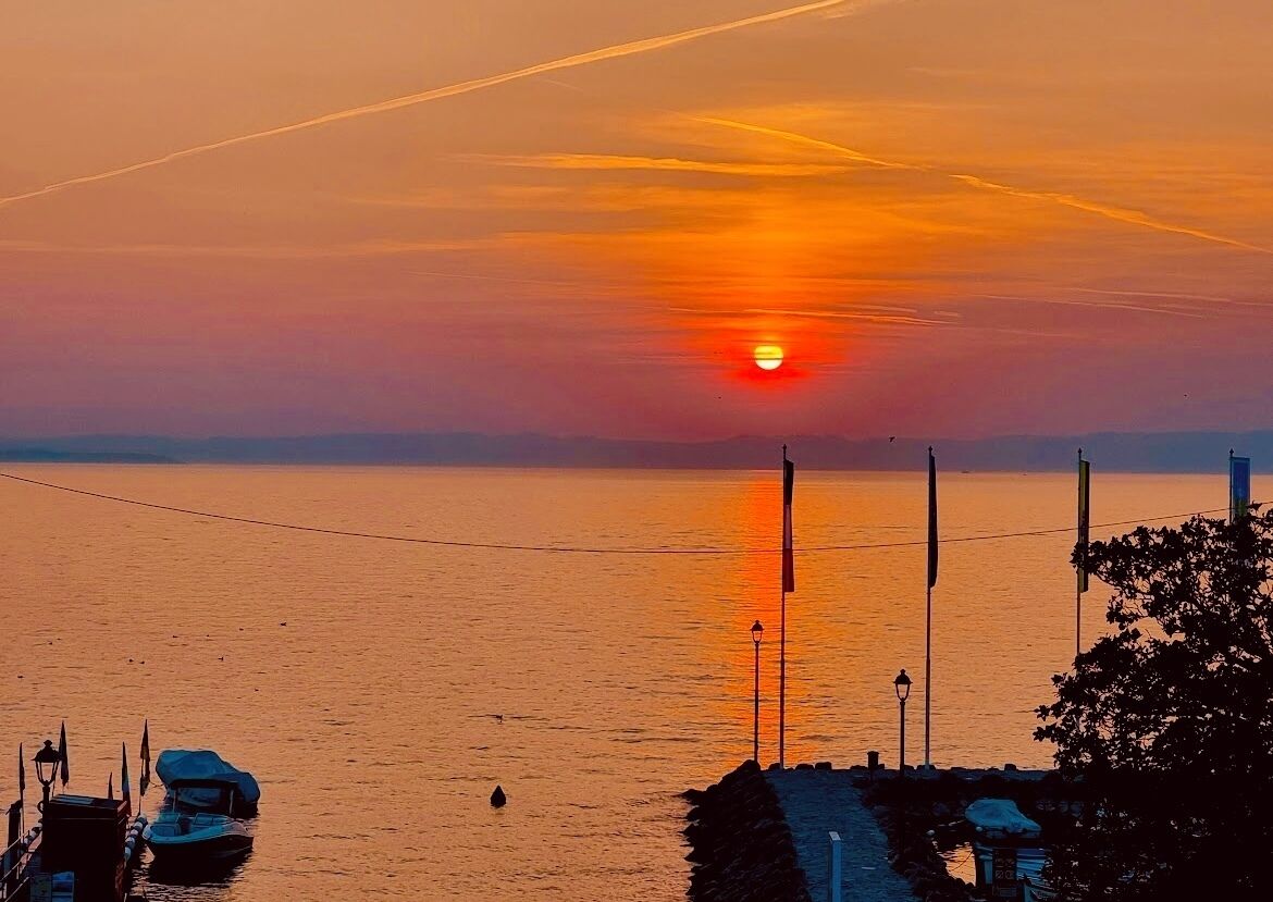 A sunset over a calm body of water with boats docked at the pier.