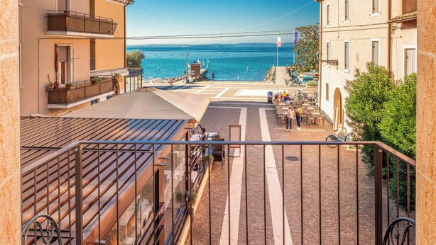 A terrace with a view of the sea, outdoor seating, and a cobblestone path. - I Tre Re (Bardolino)