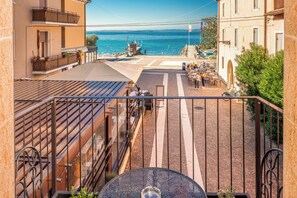 Una terraza con vistas al mar, mobiliario exterior y un camino empedrado.