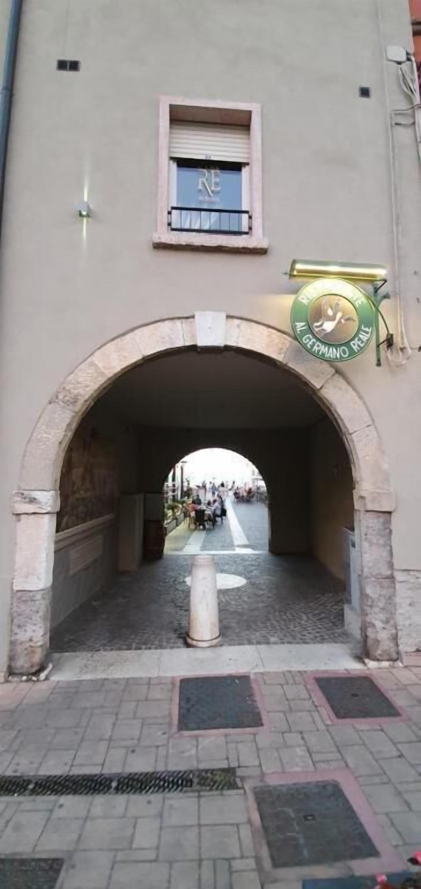 Une entrée en arc donnant sur un bâtiment, avec une enseigne au-dessus.