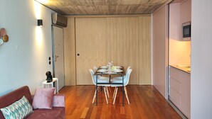A compact living space with a dining area, kitchenette, and a sofa with cushions. - Fervença Apartments - Corgo (Vila Nova de Gaia)