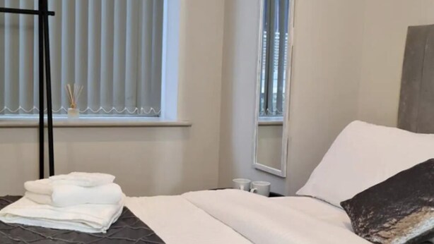 A hotel room with two beds, a window with blinds, a mirror, and towels on the beds. - Charming 1-bed, Sleeps 2, Parking (Leeds)