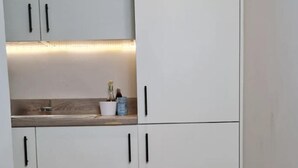 A compact kitchen with white cabinets, a wooden countertop, and a built-in oven. - Charming 1-bed, Sleeps 2, Parking (Leeds)