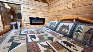 Ein Schlafzimmer in einer Blockhütte mit Bett, Kissen, Fernseher und einem hölzernen Kopfteil.