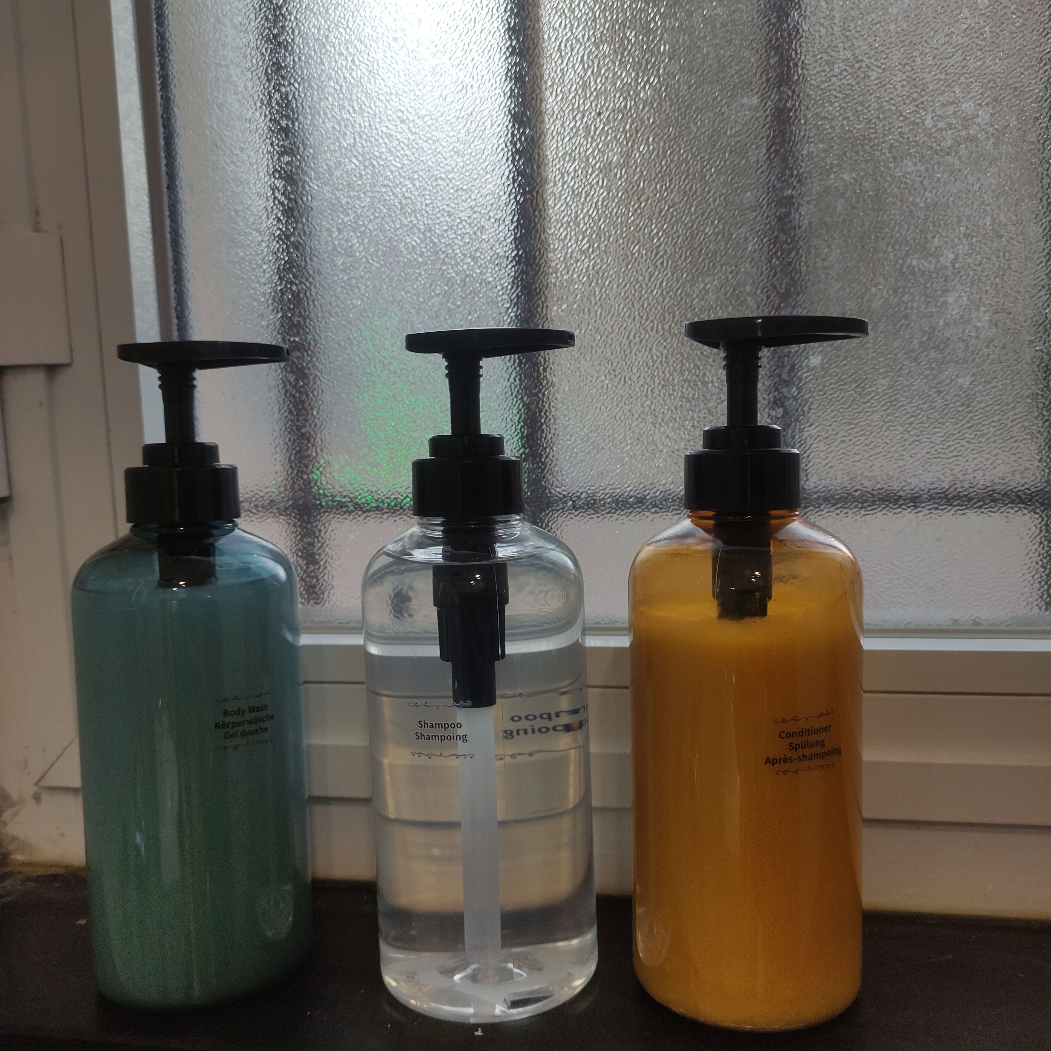 Three bottles of liquid on a windowsill.