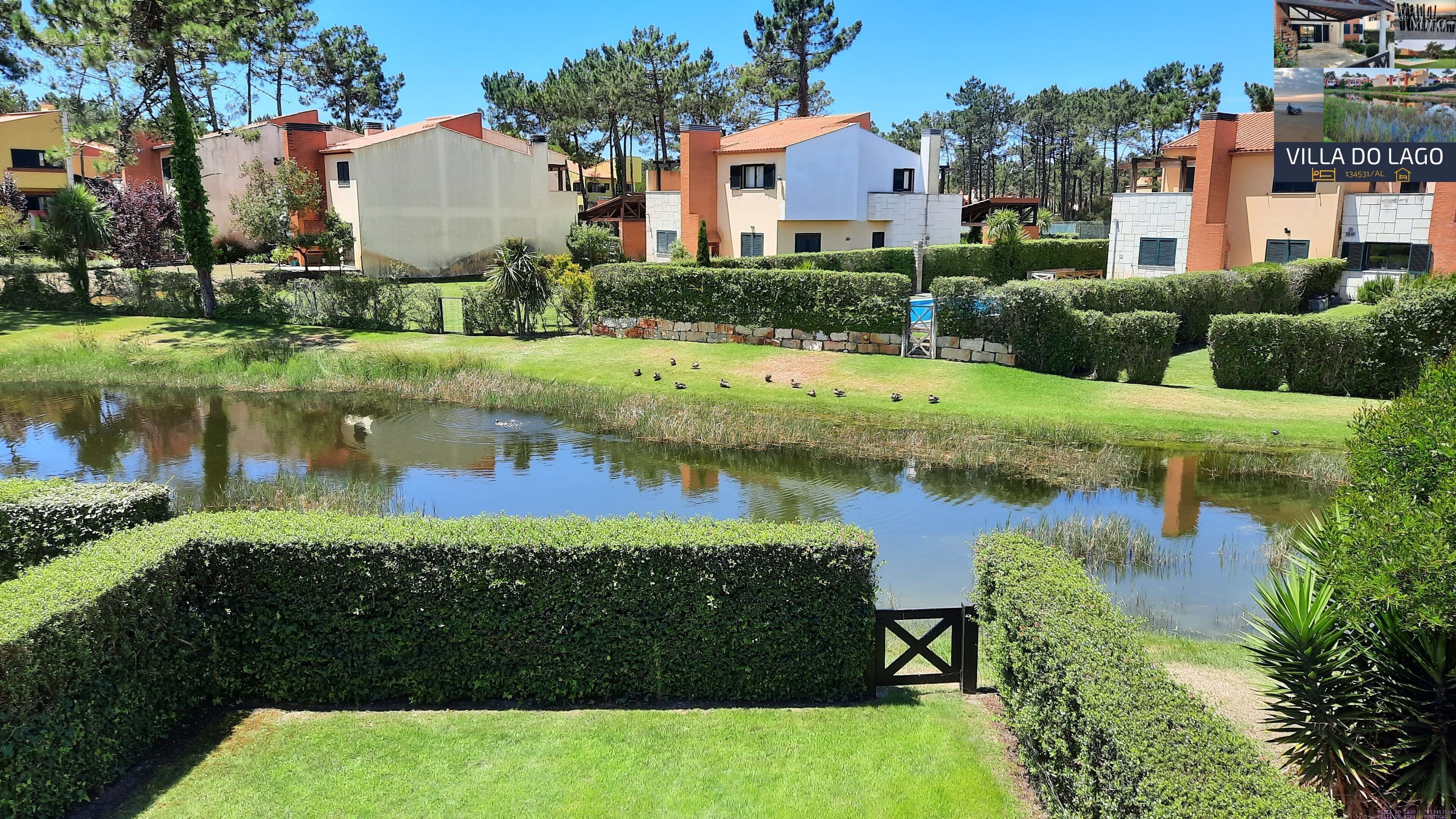 A lakeside property with manicured lawns, a pond, and modern buildings in the background.
