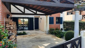 A covered patio area with a brick wall, a wooden pergola, and a tiled floor.