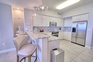 Una cocina moderna con armarios blancos, encimera de mármol y electrodomésticos de acero inoxidable.