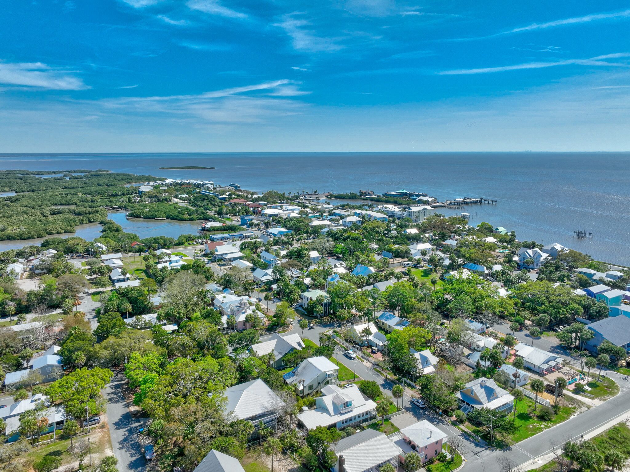 An aerial view of a coastal residential area with houses, roads, and a marina.