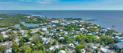 An aerial view of a coastal residential area with houses, roads, and a marina.