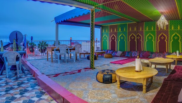 Una terraza con piso estampado, mobiliario exterior con cojines y vista al mar.