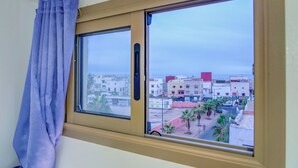 Ventana con vista a una zona residencial, con edificios y palmeras.