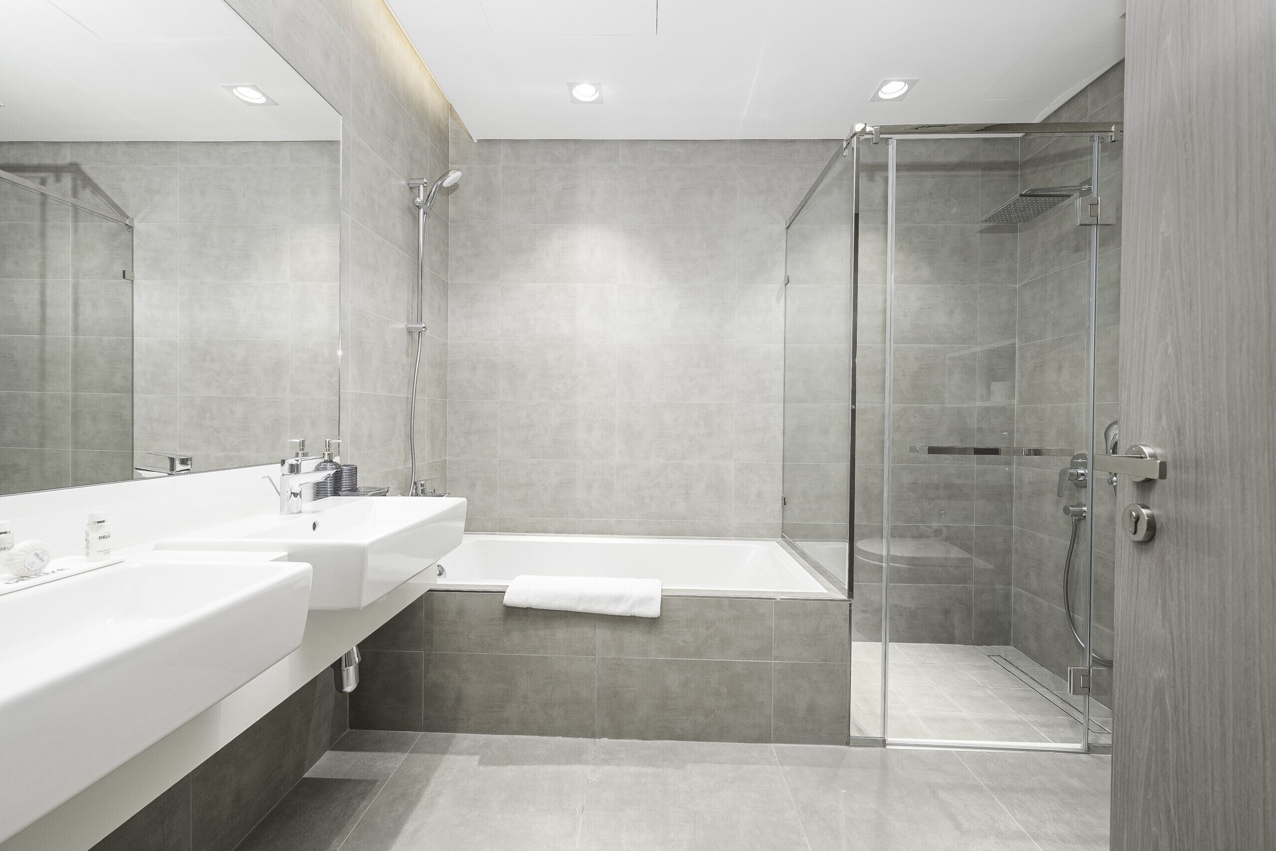 Un bagno moderno con cabina doccia in vetro, una vasca da bagno e un mobile lavabo con due lavandini.