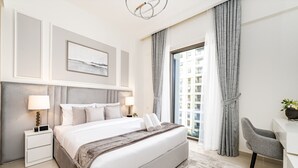A modern hotel room with a large bed, a desk, and a view of the city.