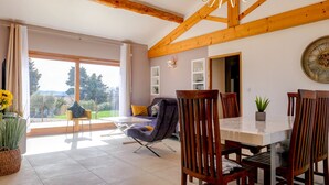 A dining area with a table and chairs, a large window with a view, and wooden beams on the ceiling. - Villa in Provence with pool, garden and Ventoux view – Colonzelle (Colonzelle)