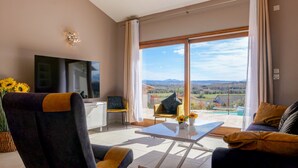 A modern living room with a large TV, comfortable seating, a glass coffee table, and a scenic view through the sliding glass door. - Villa in Provence with pool, garden and Ventoux view – Colonzelle (Colonzelle)